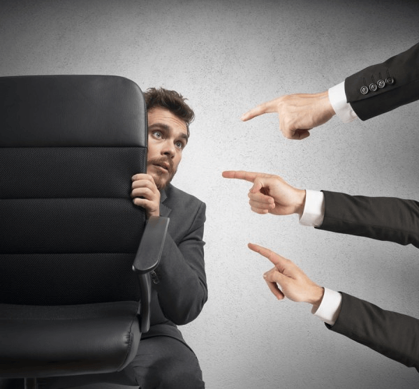 Mężczyzna schowany za fotelem w obawie przed krytyką